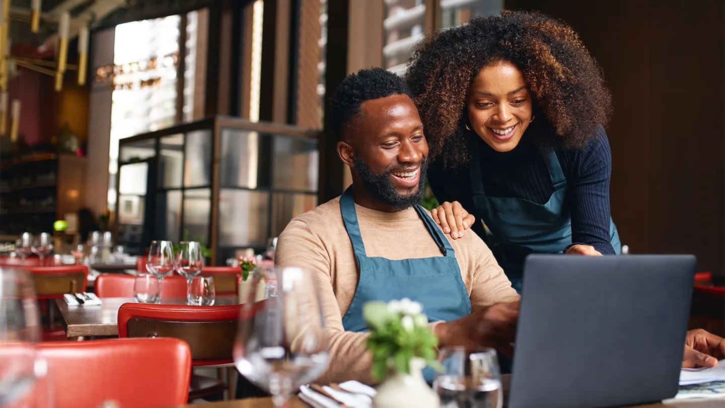 Two hospitality owners reviewing marketing plans on a laptop