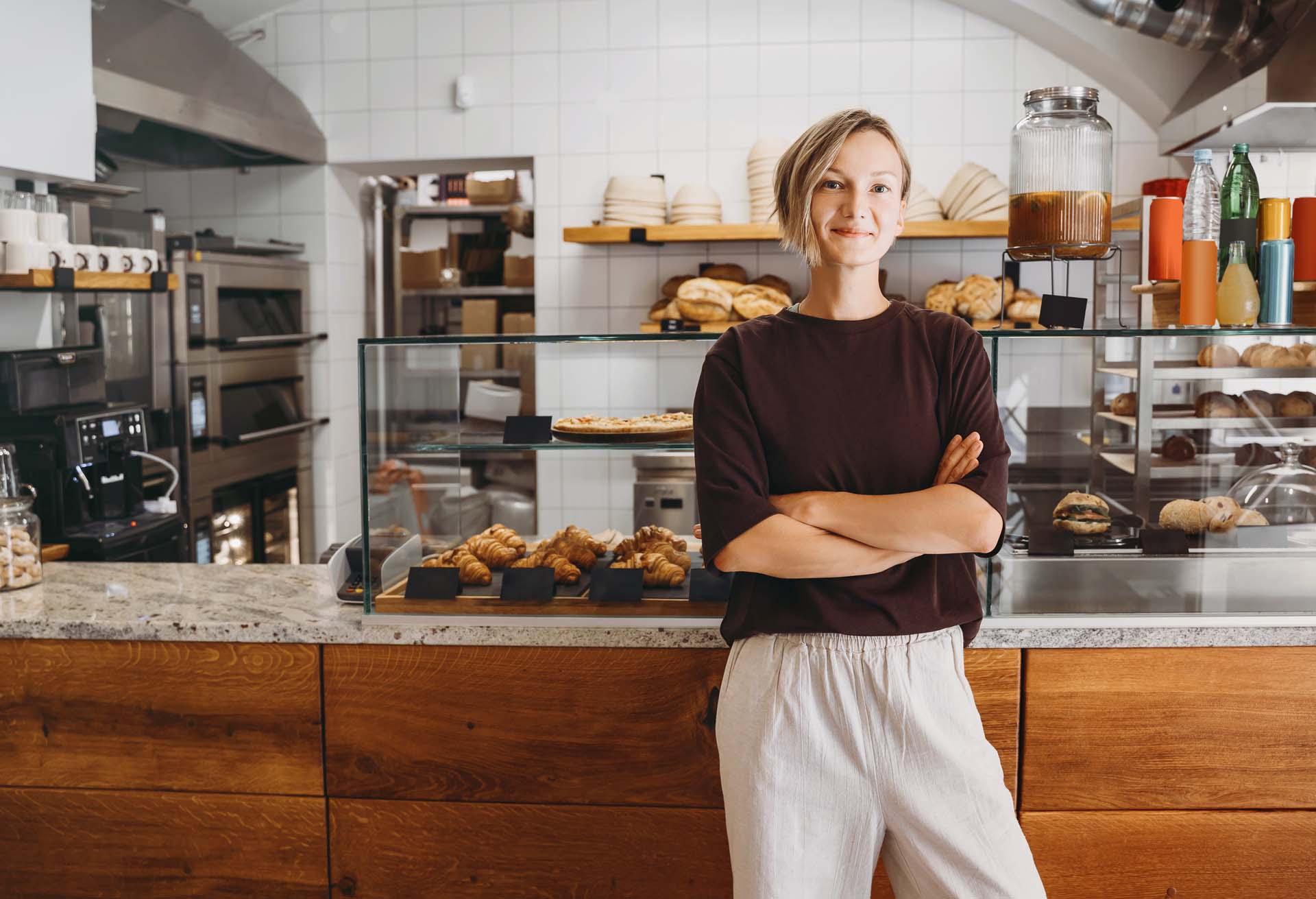 A young bakery owner standing proudly in front of her counter
